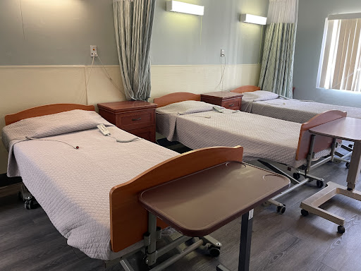 A view of a hospital patient room with multiple beds and medical equipment.