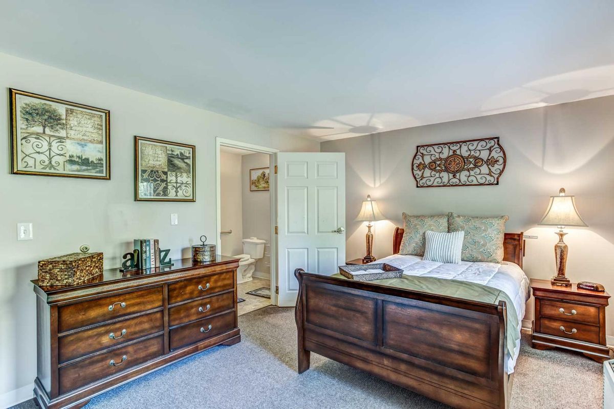 A cozy bedroom with a wooden bed, dresser, and decorative artwork on the walls.