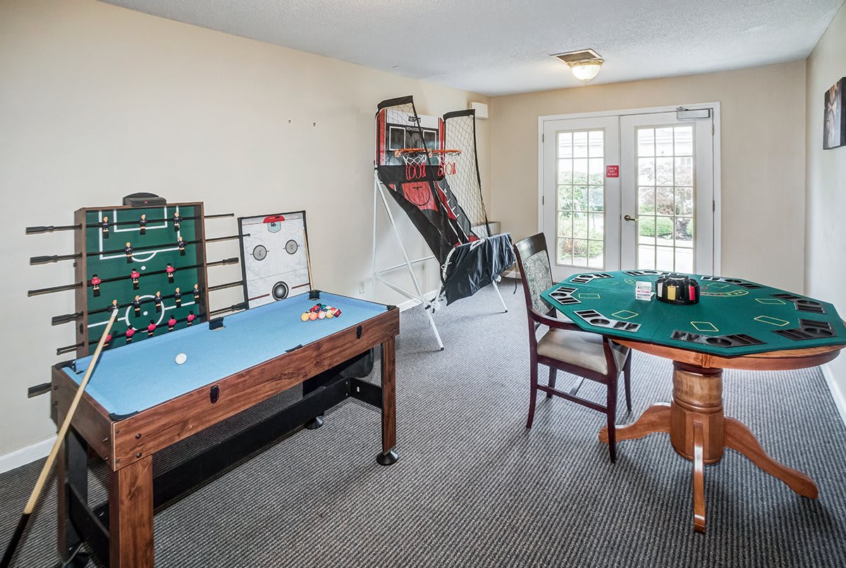 A game room with various table games and an arcade basketball setup.