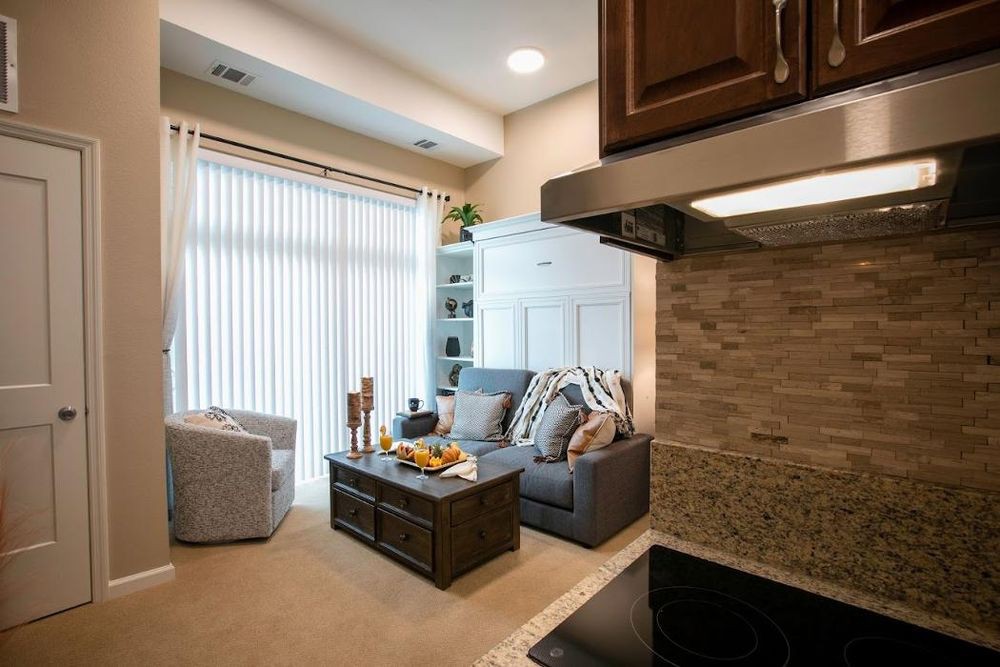 A modern living room with a cozy sofa, coffee table, and adjacent kitchen.