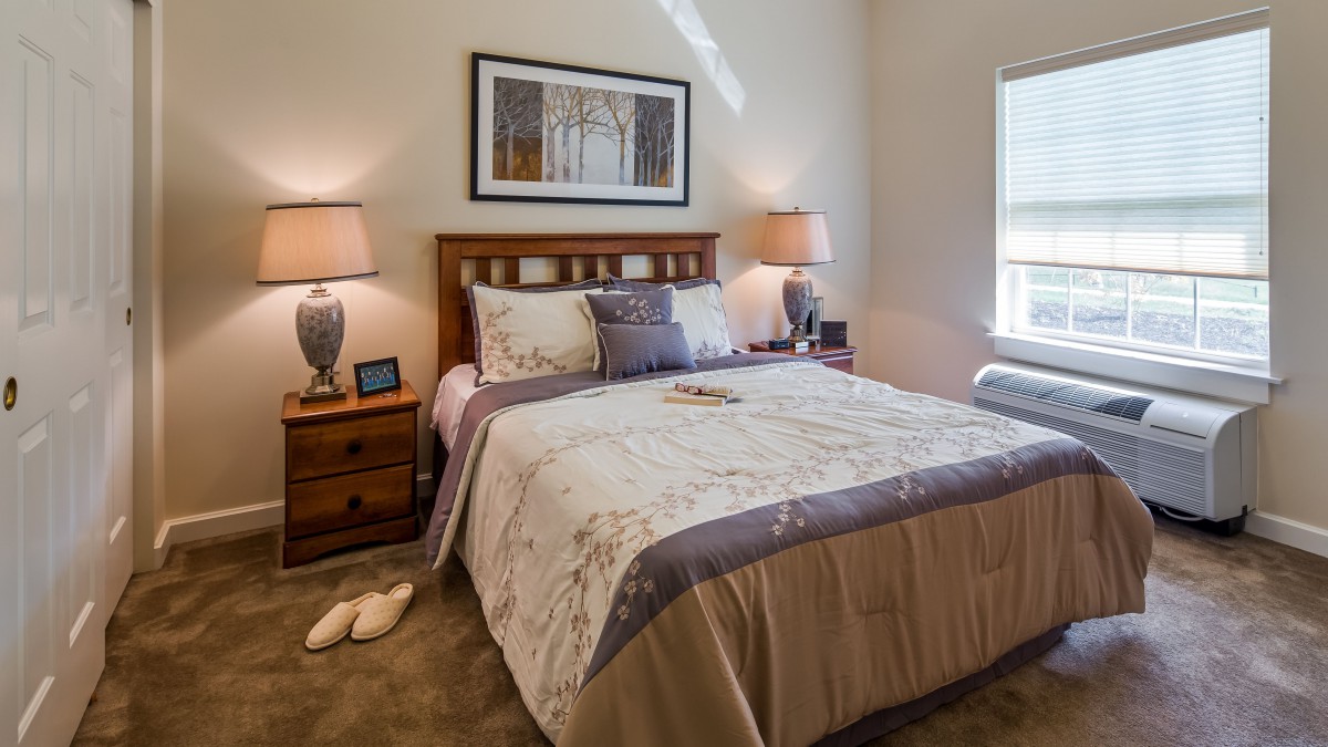 A cozy bedroom interior with a neatly made bed and two bedside lamps.