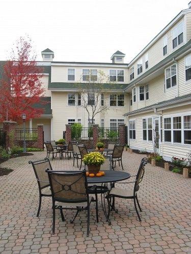An outdoor courtyard with tables and chairs surrounded by a multi-story building.