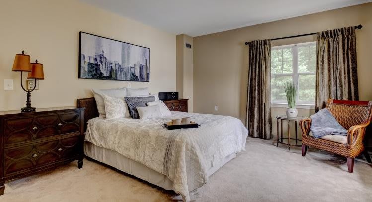 A cozy bedroom featuring a neatly made bed, elegant curtains, and wall artwork.