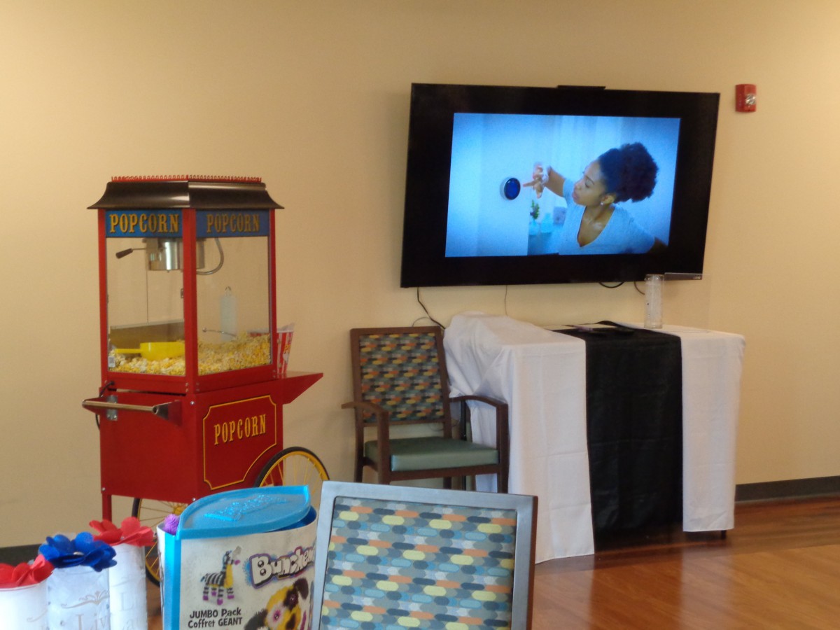 Indoor event setup with a popcorn machine and a TV screen.