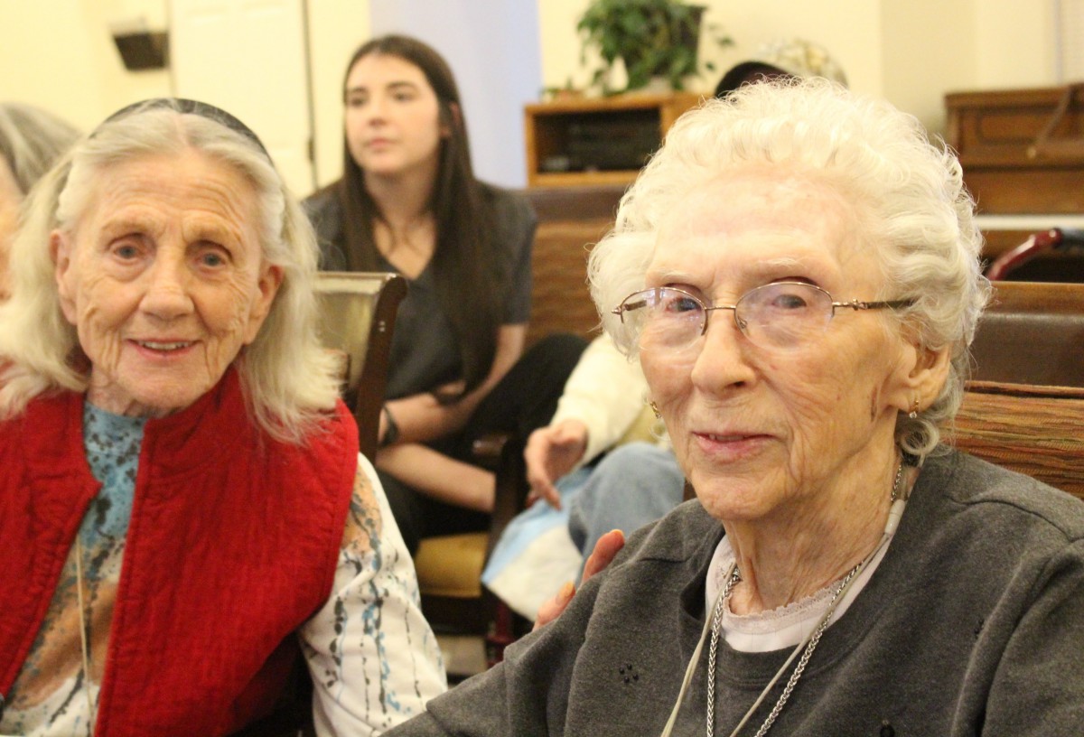 Elderly women sitting together at a community gathering.