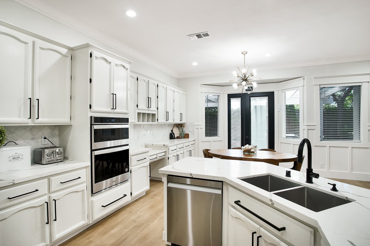 A modern kitchen featuring white cabinets, an island, and stainless steel appliances.