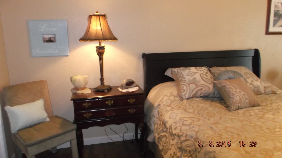 A cozy bedroom scene with a bed and a nightstand featuring a lamp.