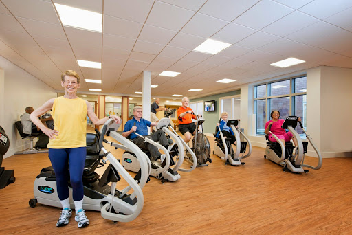 A vibrant gym scene featuring individuals engaged in a group workout session on exercise machines.
