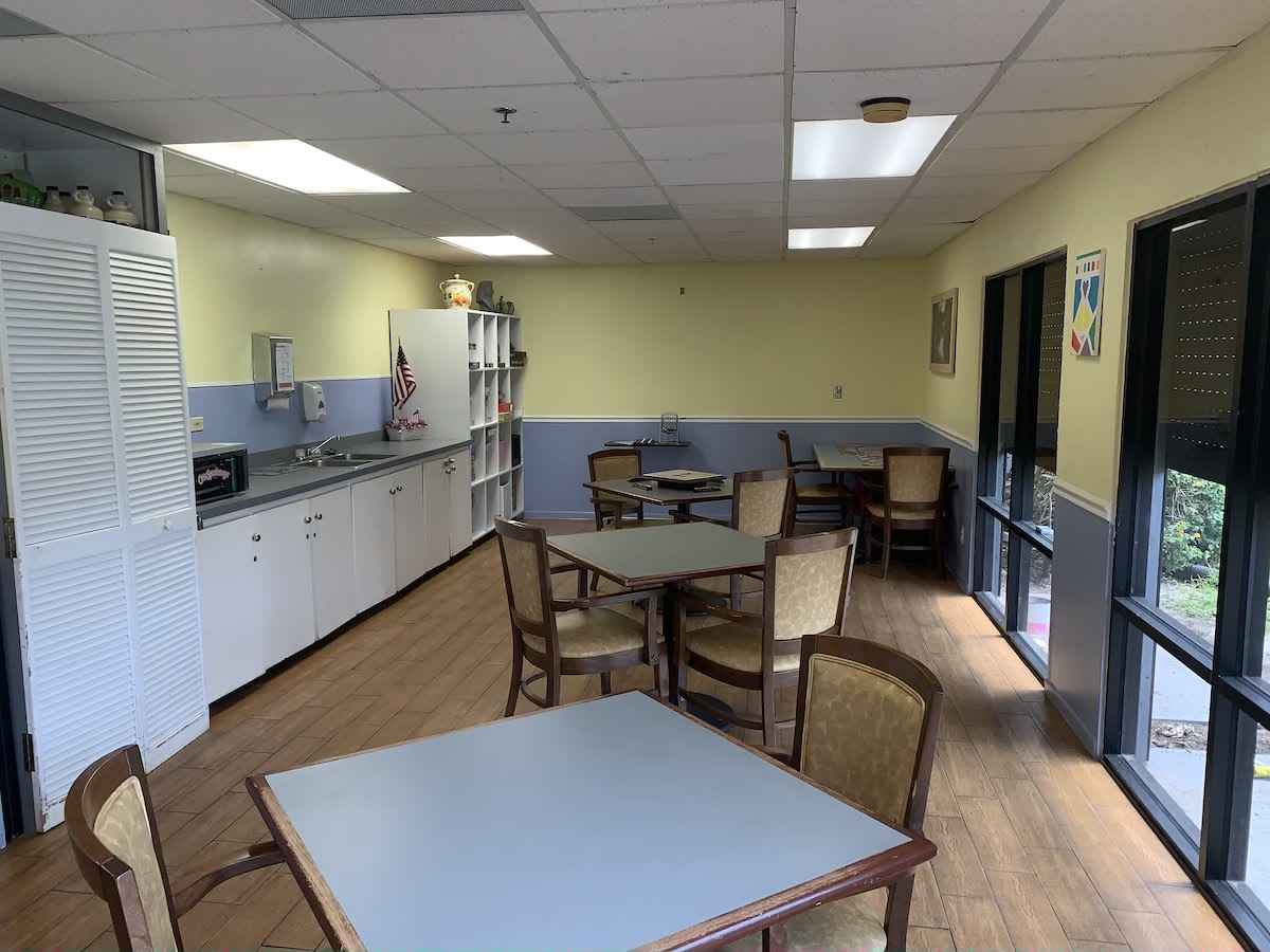 A well-lit break room with tables, chairs, and a kitchenette.