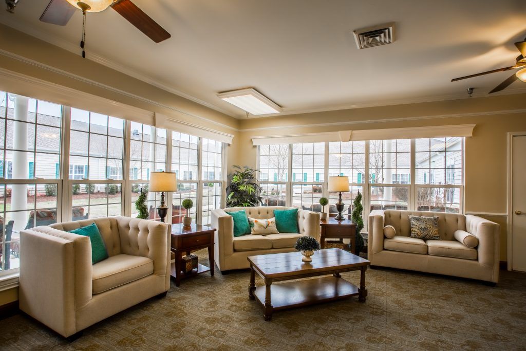 A cozy living room with large windows, beige sofas, and a wooden coffee table.