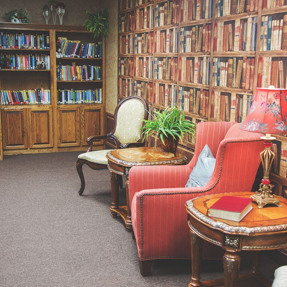 A cozy library corner with bookshelves, an armchair, and a lamp.