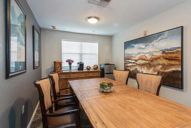 A well-decorated dining room with a wooden table, chairs, and a landscape painting on the wall.