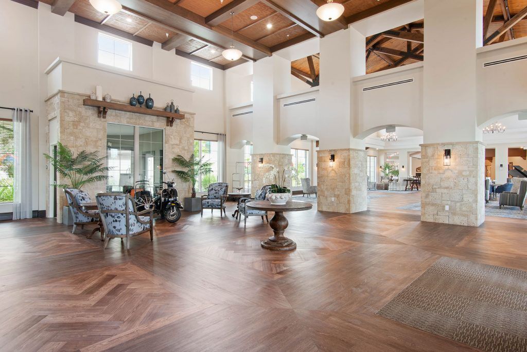 Spacious lobby area with elegant wood flooring and high ceilings, featuring stylish furniture and decor.