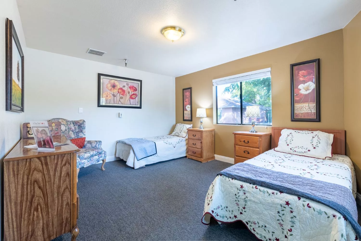 A cozy bedroom with two twin beds, featuring wooden furniture and a large window providing natural light.