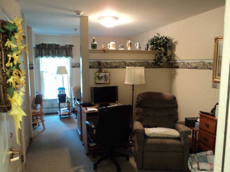 A cozy living room with a comfortable chair, desk, and decorative items on the shelf.