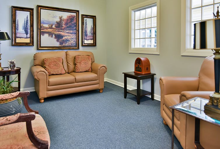 A cozy living room with leather sofas, a carpeted floor, and wall art.