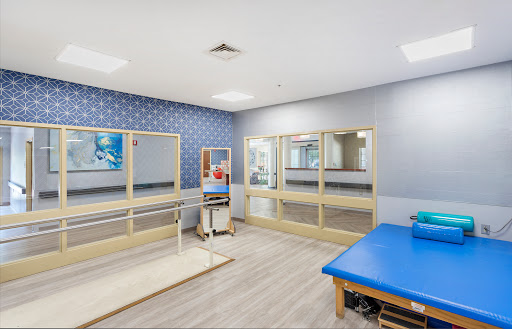 A well-equipped physical therapy room featuring mirrors, a treatment table, and various exercise tools.