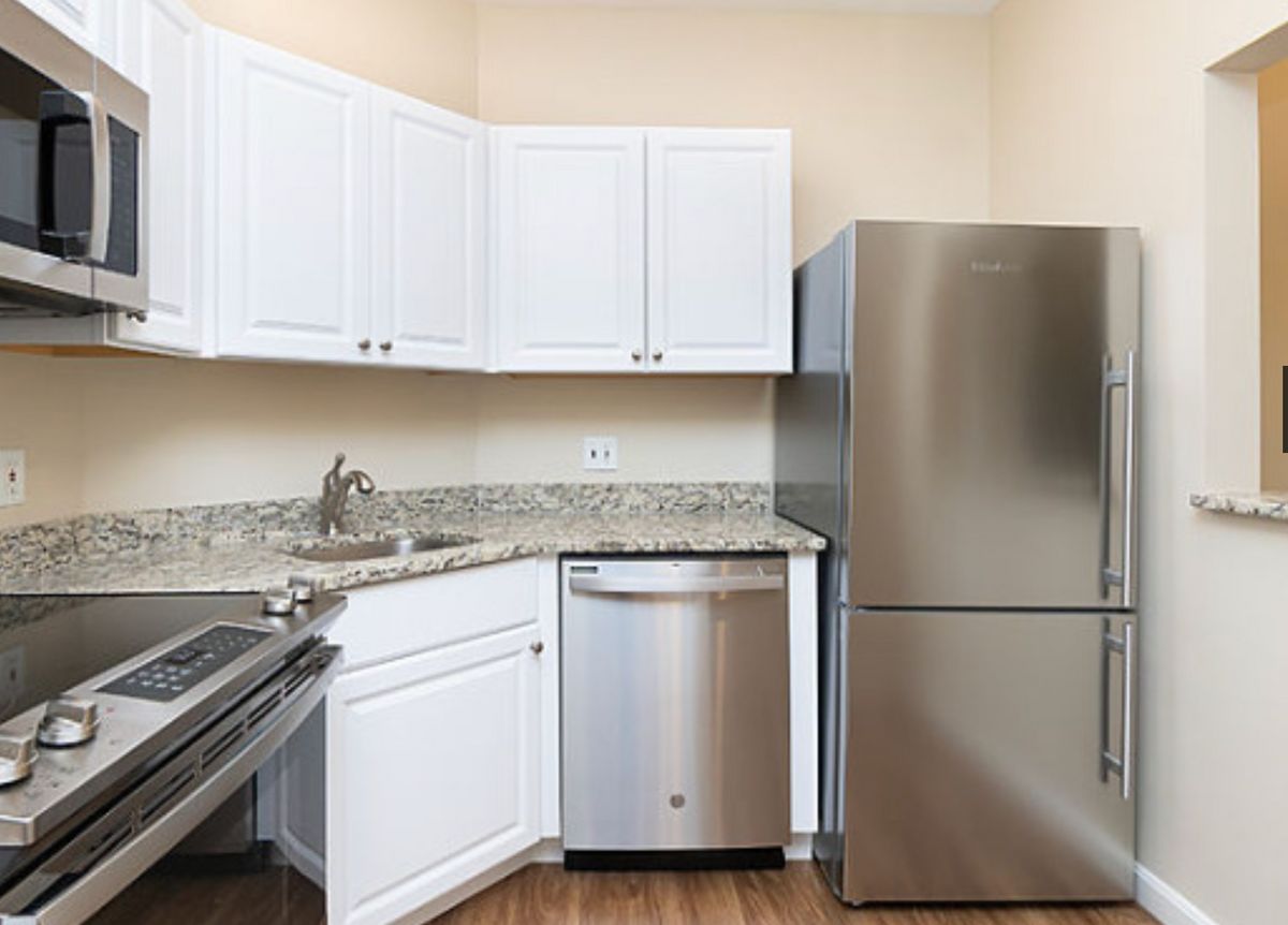 A modern kitchen featuring white cabinets, stainless steel appliances, and a granite countertop.