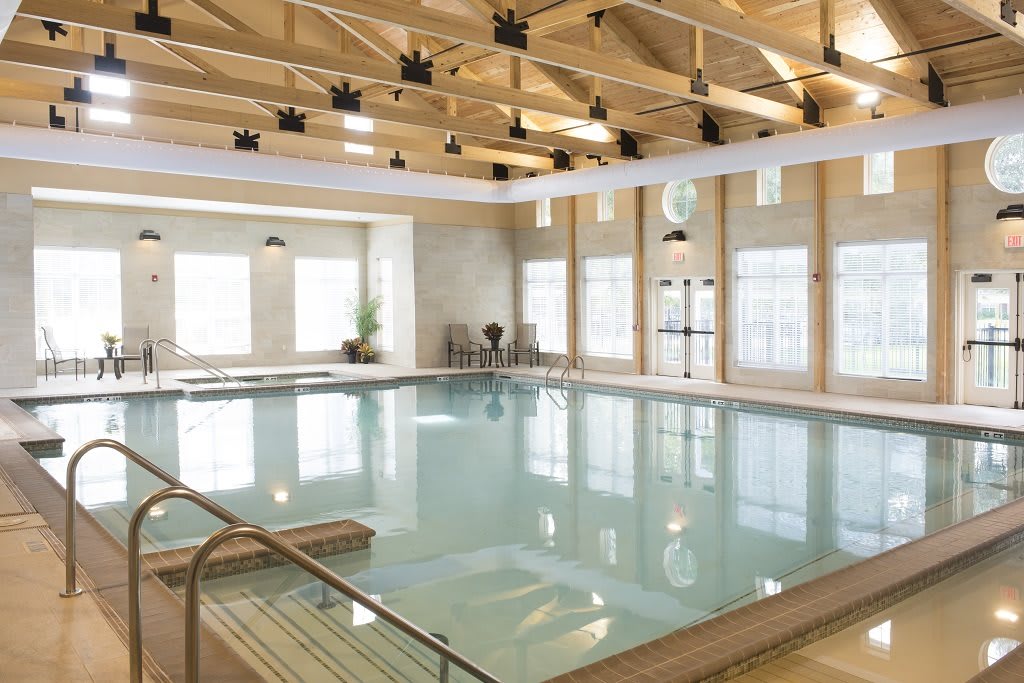 A spacious indoor swimming pool with a modern design and abundant natural light streaming through large windows.