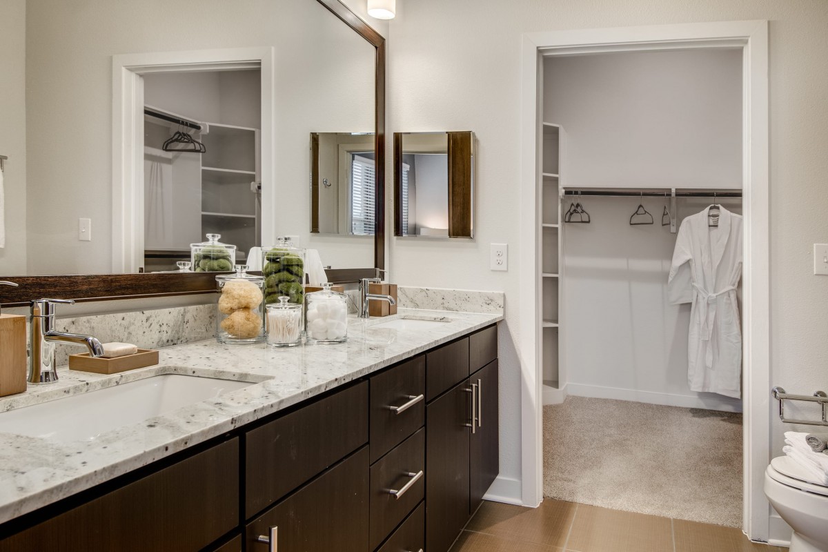 A modern bathroom with a marble countertop and adjacent walk-in closet.