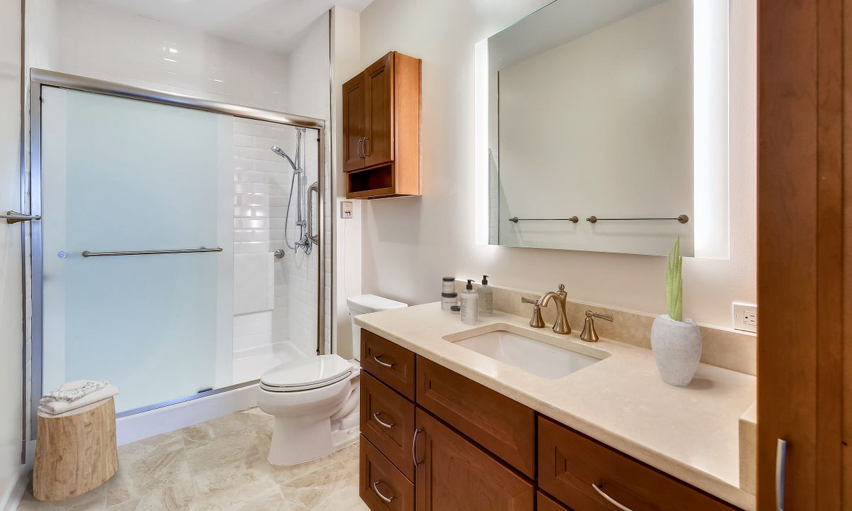 A modern bathroom with a walk-in shower, vanity sink, and wooden cabinets.