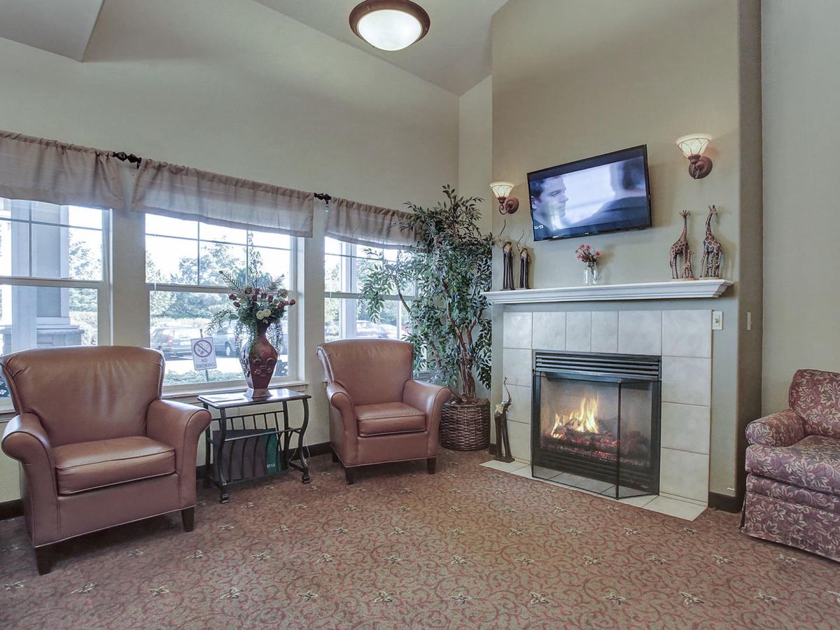 A cozy living room with a fireplace, armchairs, and a TV.