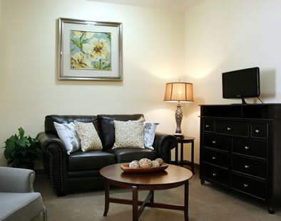A cozy living room with a leather sofa, coffee table, and wall art.