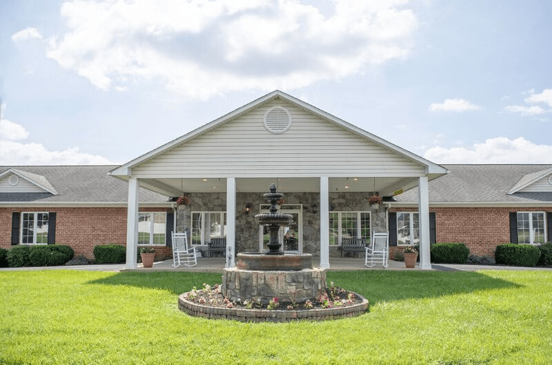 A suburban house with a front porch and a fountain on the lawn.