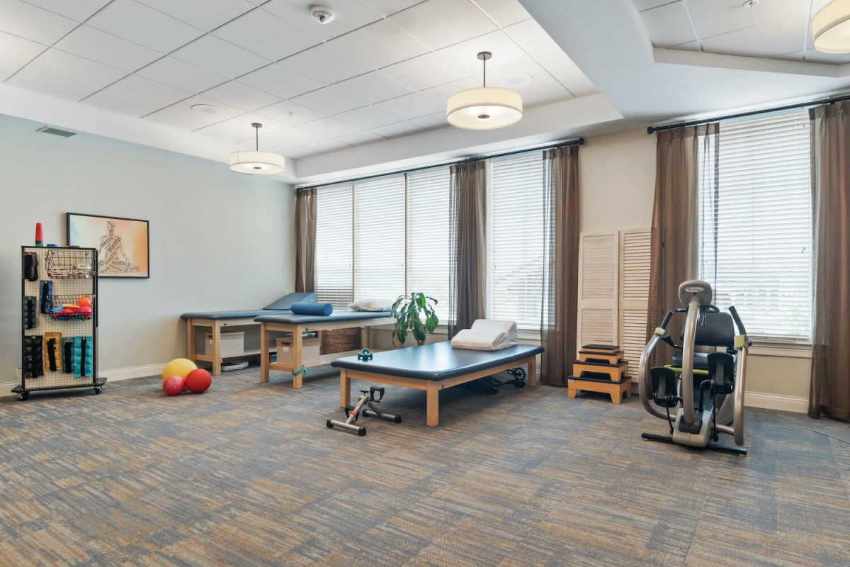 A well-lit physical therapy room equipped with treatment tables and exercise equipment.