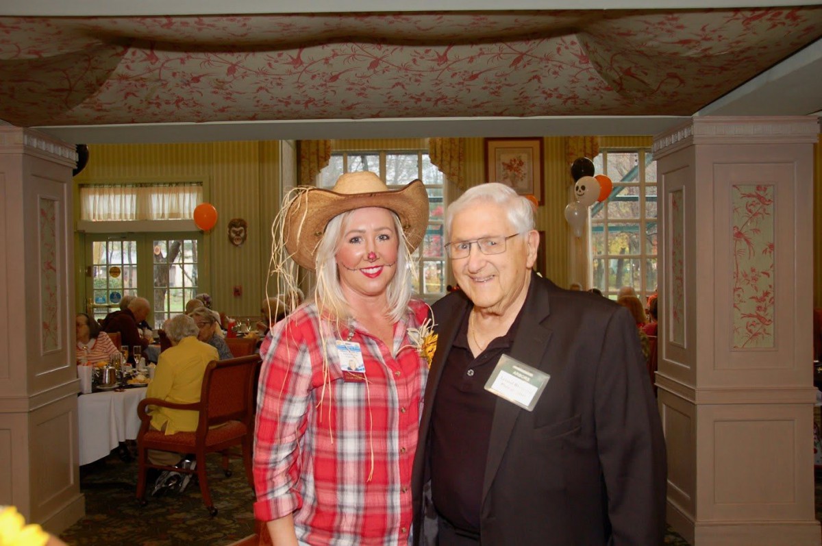 Two people posing together at an indoor event, one wearing a cowboy hat and plaid shirt.