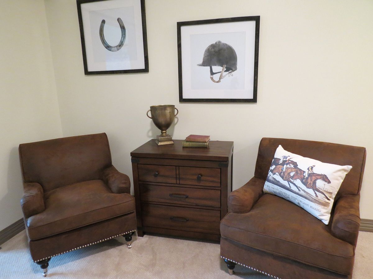 A cozy living room corner with two brown chairs, a side table, and framed artwork on the wall.