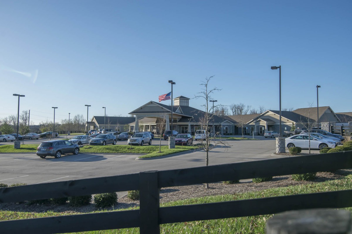A building with a parking lot and several cars under a clear blue sky.