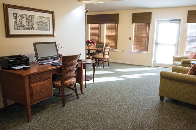 A sunlit office space with desks, chairs, and a computer.