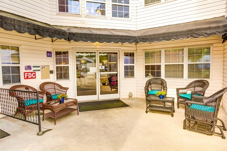 A welcoming entrance with comfortable outdoor seating and large windows.