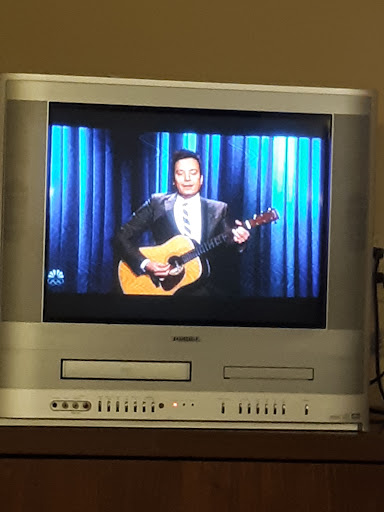 A performer singing with a guitar on a television screen.