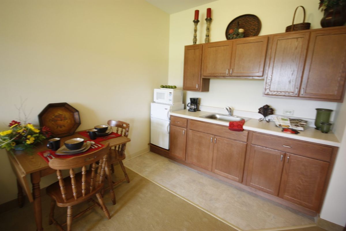 A cozy kitchen with wooden cabinets, dining table, and essential appliances.