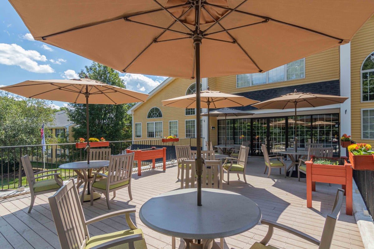 A sunny outdoor patio with tables, chairs, and umbrellas.