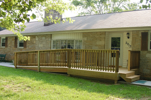 A cozy house featuring a wooden deck that extends into the grassy yard.