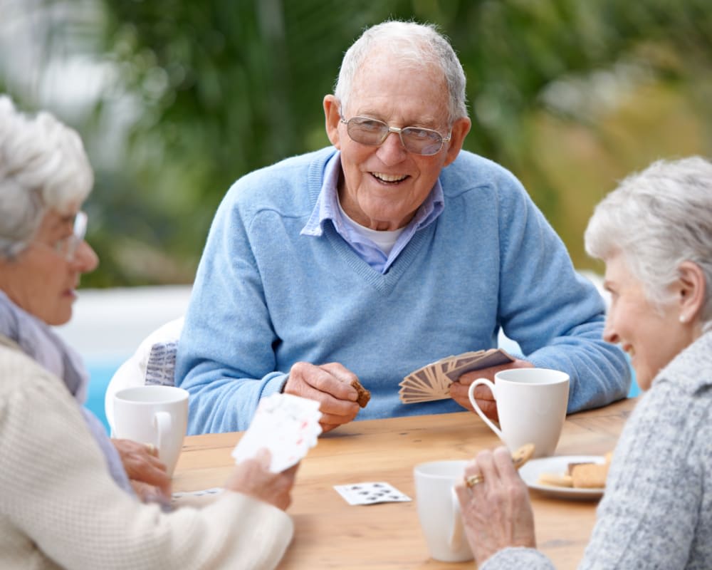 A group of seniors enjoying a game of cards and coffee outdoors.
