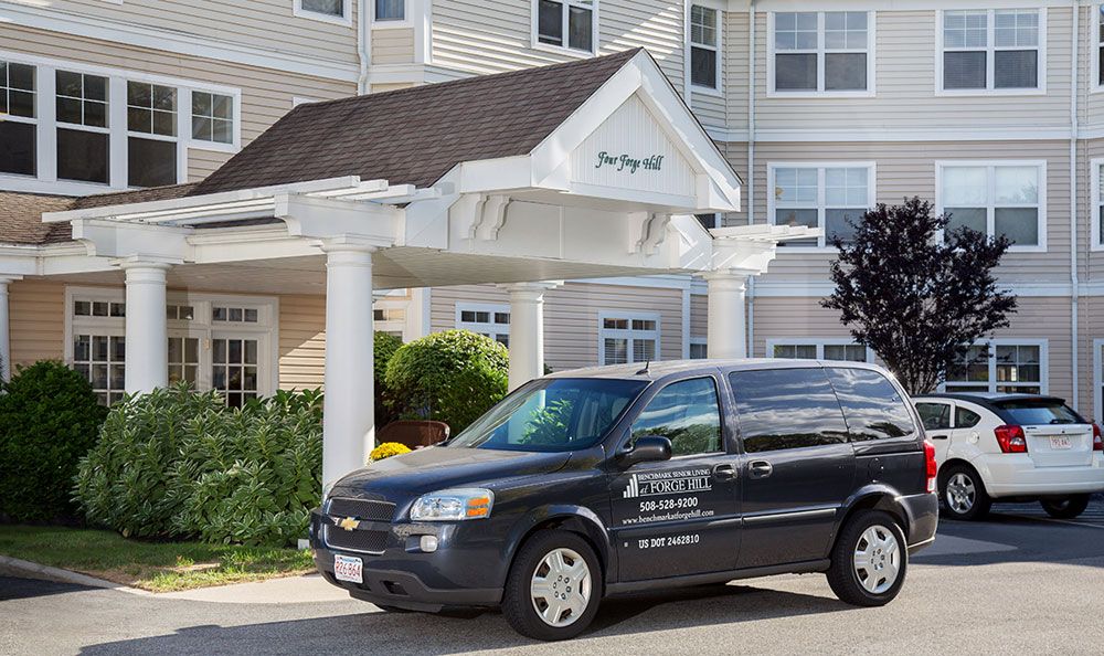 A hotel shuttle van parked in front of a building's entrance.