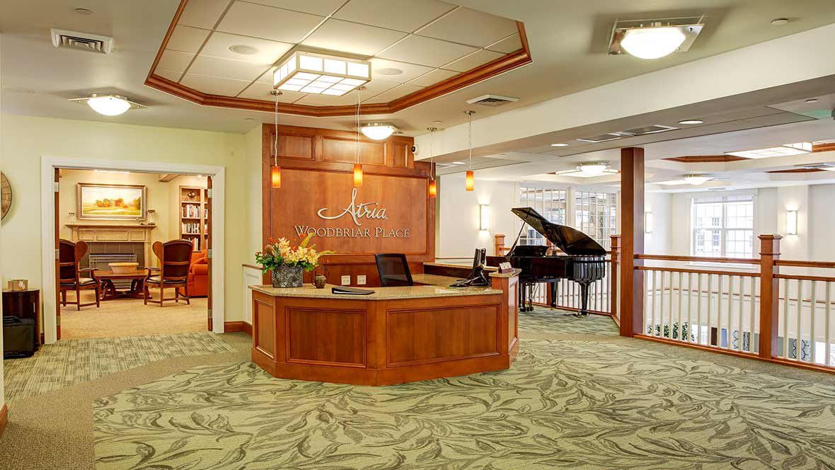 A welcoming hotel lobby with a reception desk and a grand piano.