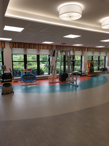 A bright and spacious rehabilitation therapy room equipped with various exercise machines and colorful flooring.
