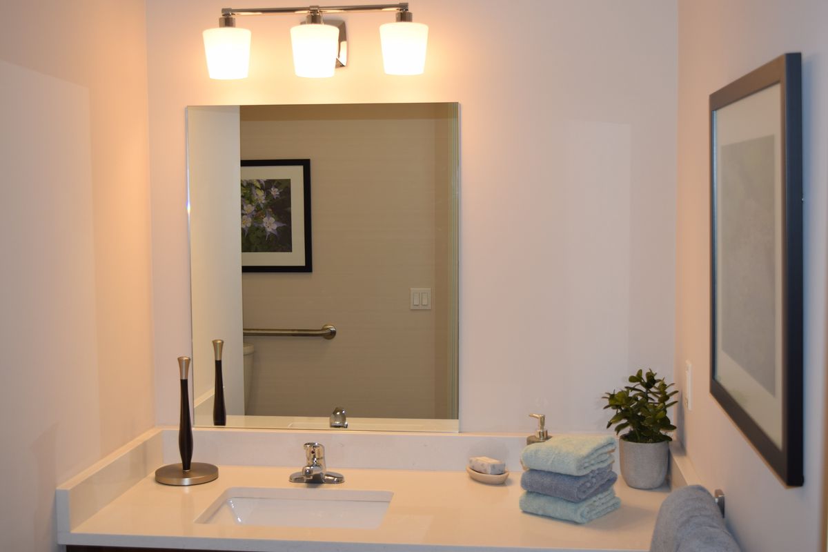 A modern bathroom with a large mirror, neatly stacked towels, and decorative elements.