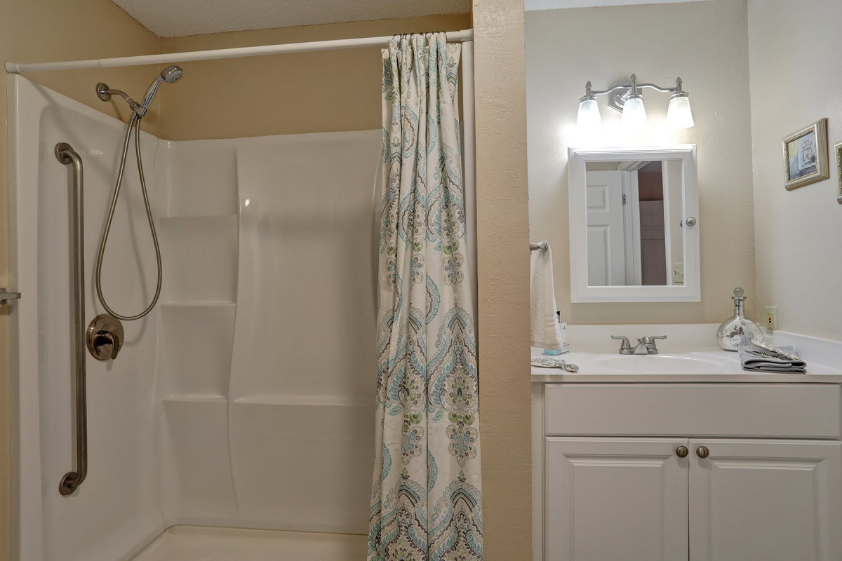 A well-lit bathroom with a shower and a small vanity area.