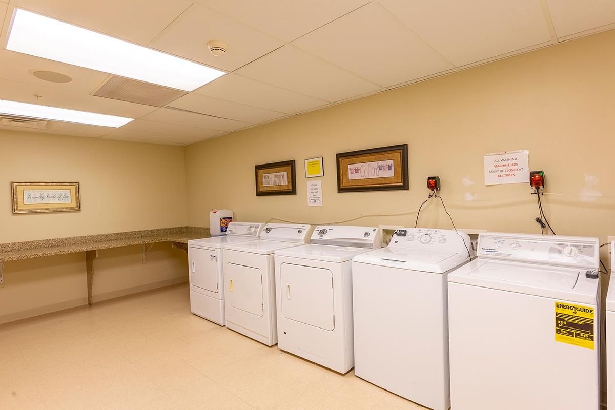 A clean and organized laundry room with several washing machines and dryers.
