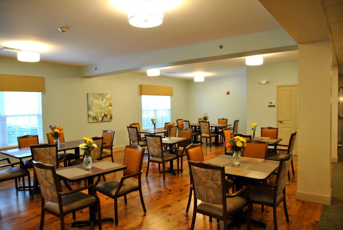 A spacious dining room with multiple tables and chairs, featuring warm lighting and elegant decor.