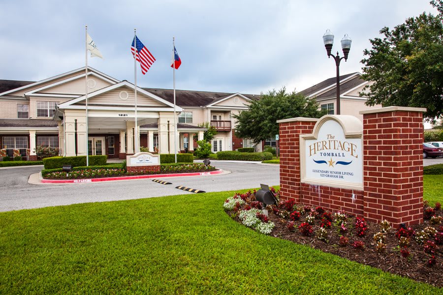 A hotel entrance with well-maintained landscaping and flags, set against a cloudy sky.