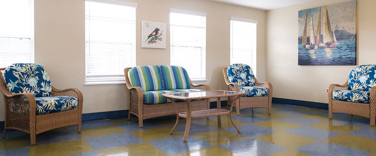 A cozy living room setup with patterned cushions on a sofa and chairs, accompanied by a glass-top table.