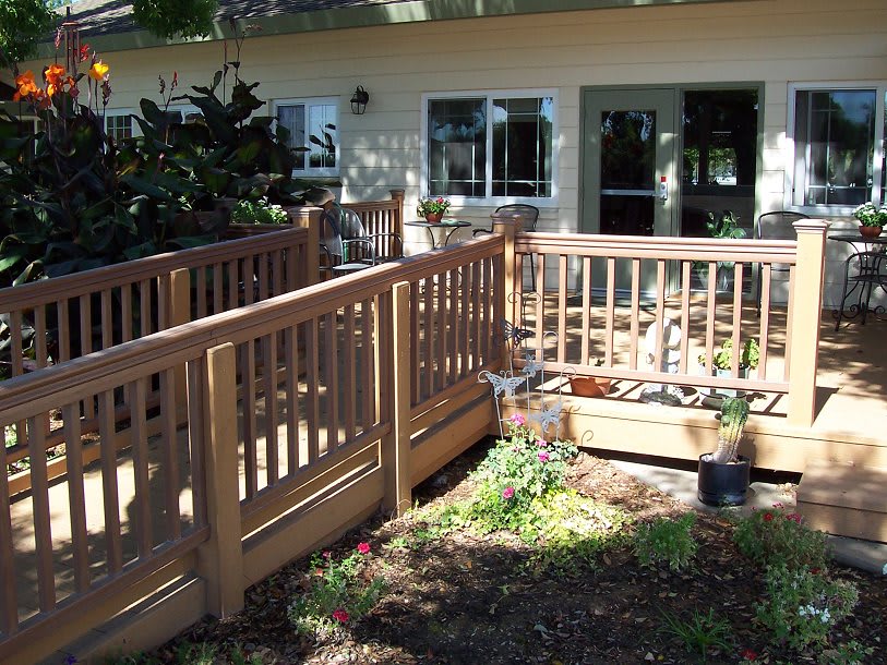 A house with a wooden ramp and railing leading to a garden area.