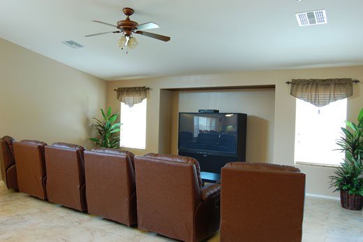 A cozy living room set up as a home theater with leather chairs facing a large TV.
